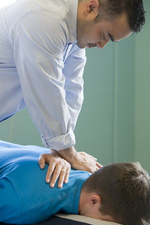 Therapist giving man neck and shoulder massage.